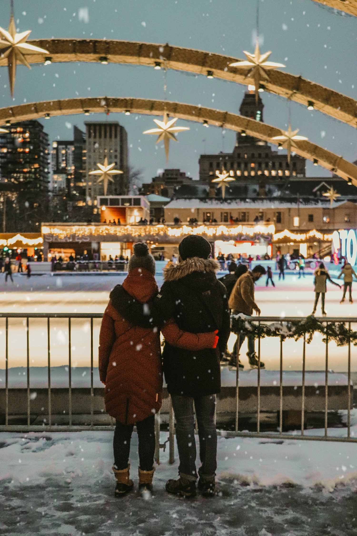 two people standing on a bridge looking at a city